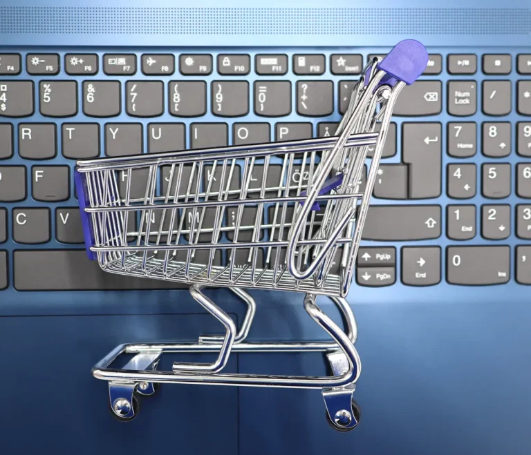 A miniature shopping cart placed on a laptop keyboard symbolizing online shopping and e-commerce